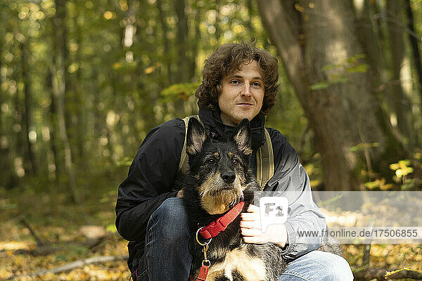 Smiling man with dog sitting in forest