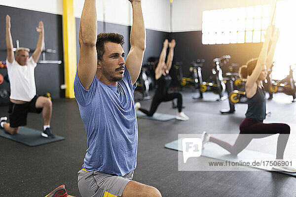 Sportler mit erhobenen Armen trainieren im Fitnessstudio