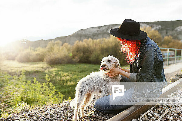 Woman stroking Border Collie dog sitting on railroad track