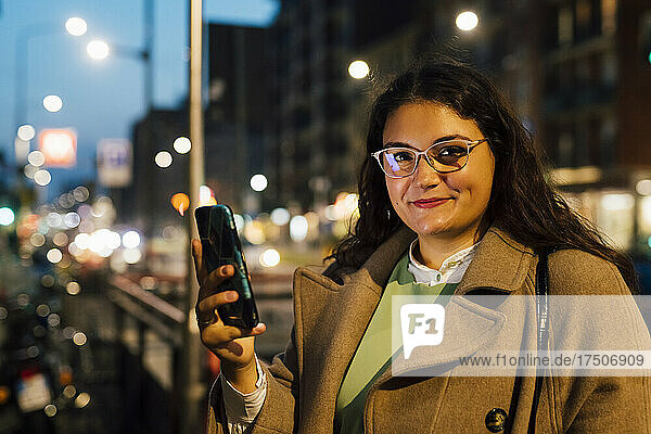 Young curvy woman wearing eyeglasses holding mobile phone