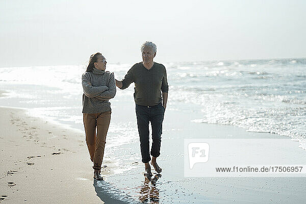 Senior man with daughter walking together at beach