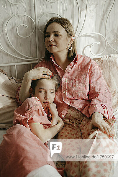 Girl relaxing with mother on bed at home