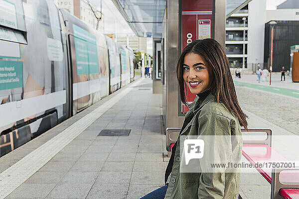 Young smiling woman at tram station platform