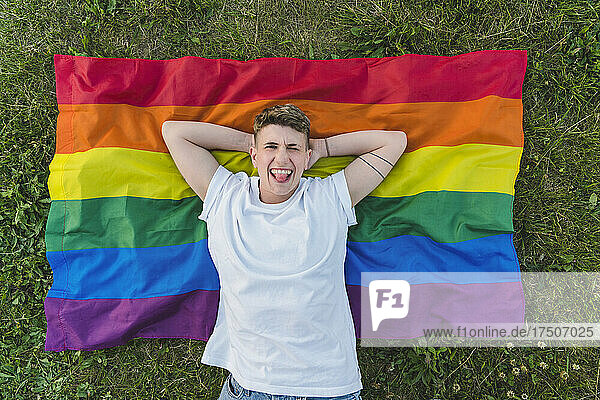 Frau mit den Händen hinter dem Kopf entspannt sich auf der Regenbogenfahne