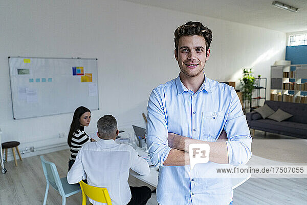 Young businessman with arms crossed in modern office