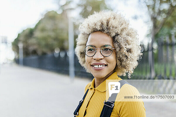 Lächelnde Frau mit Brille und Afro-Frisur auf Fußweg