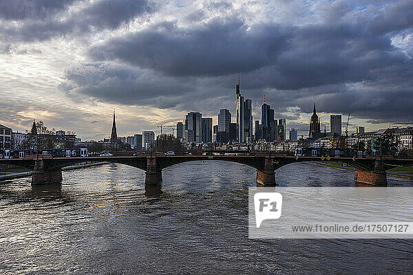 Germany  Hesse  Frankfurt  Cloudy sky over Ignatz Bubis Bridge at dusk with downtown skyline in background