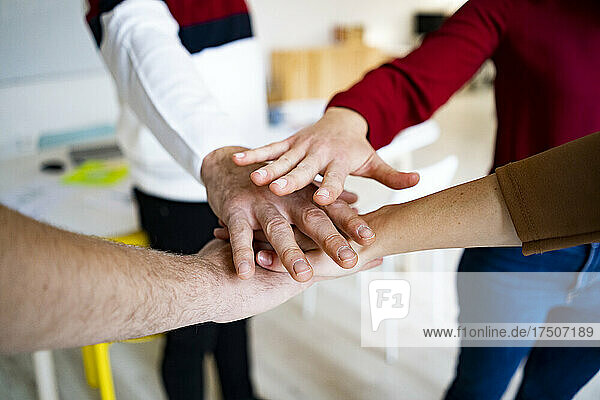 Team of colleagues stacking hands in office