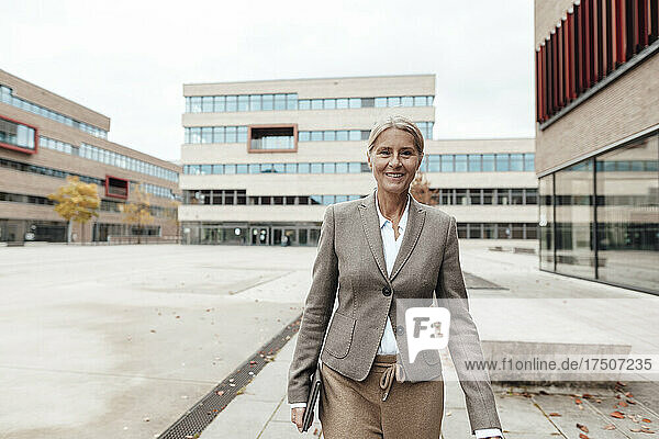 Lächelnde Geschäftsfrau mit Tablet-PC geht auf Fußweg