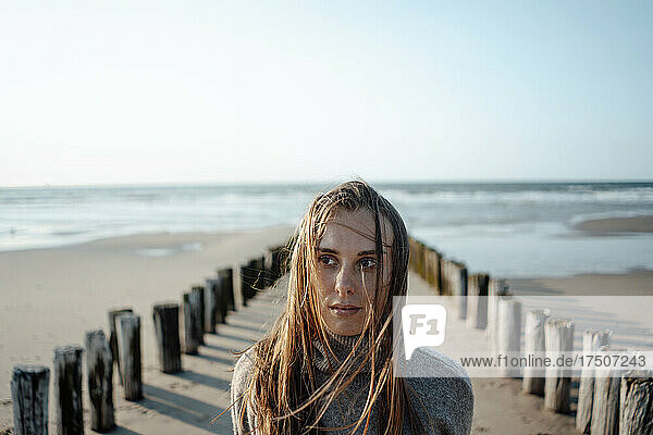 Serious woman near wooden posts at beach