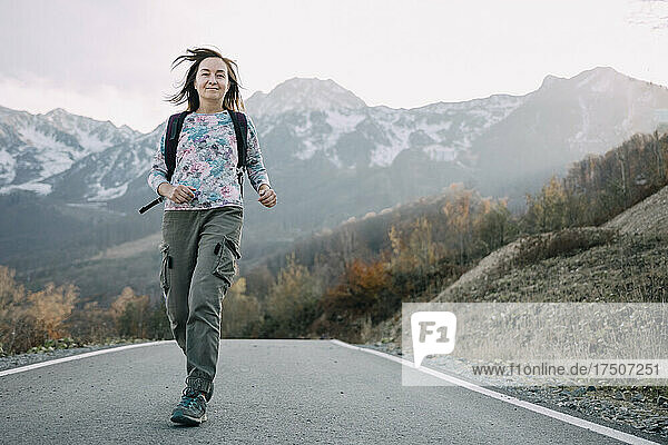 Woman with backpack running on mountain road