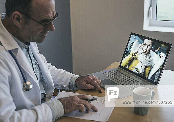 Doctor discussing medical reports with patient on video call through laptop in clinic