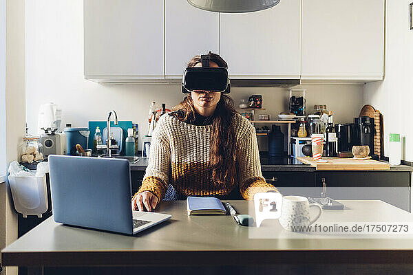Woman with virtual reality headset sitting at desk at home