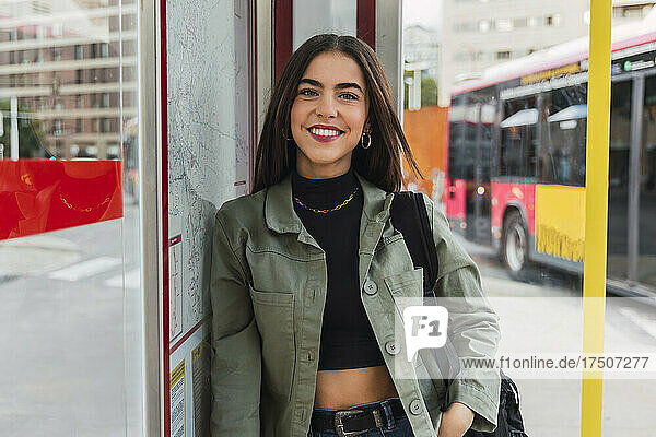 Lächelnde Frau mit Jacke an Bushaltestelle