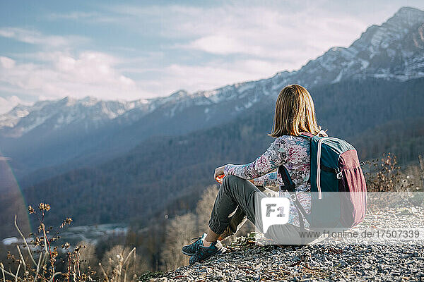 Tourist with backpack resting on mountain