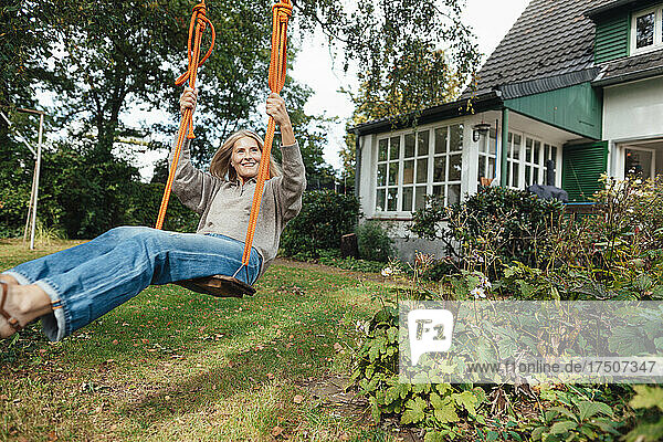 Woman swinging on play equipment at backyard
