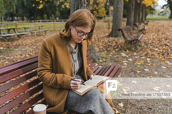 Young woman writing in book in public park