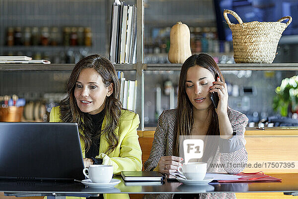 Coworkers with laptop and smart phone working at cafe table