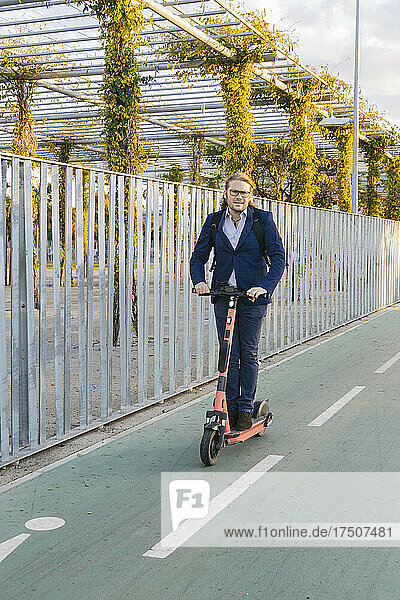 Businessman riding push scooter on road