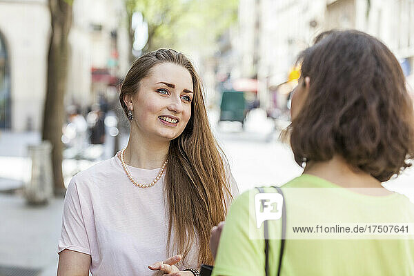 Beautiful woman talking with friend on footpath