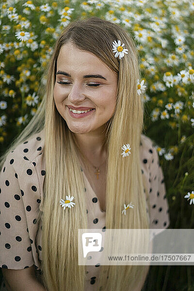 Happy woman with eyes closed wearing flowers on long blond hair