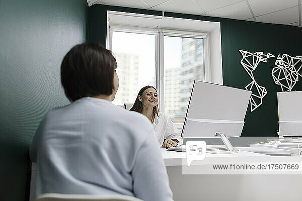 Client and travel agent discussing at desk in office