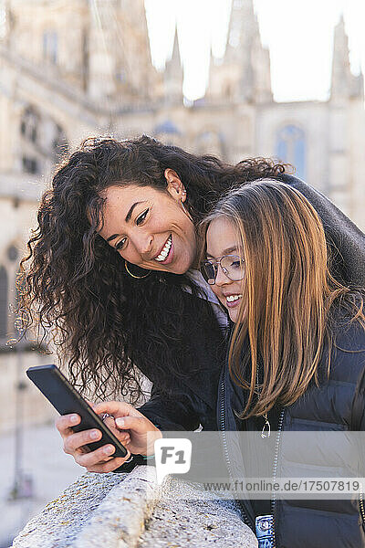 Smiling mother and daughter using smart phone at Burgos Cathedral  Burgos  Spain