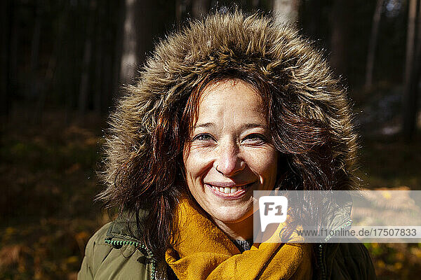 Smiling woman with fur cap in forest