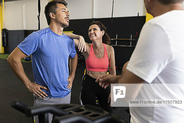 Smiling woman leaning on shoulder of man in gym