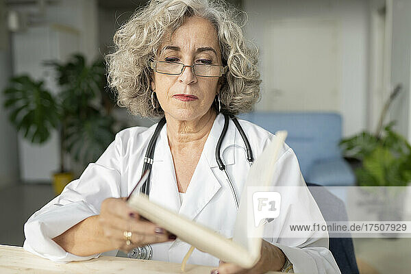 Senior senior doctor reading diary at home office