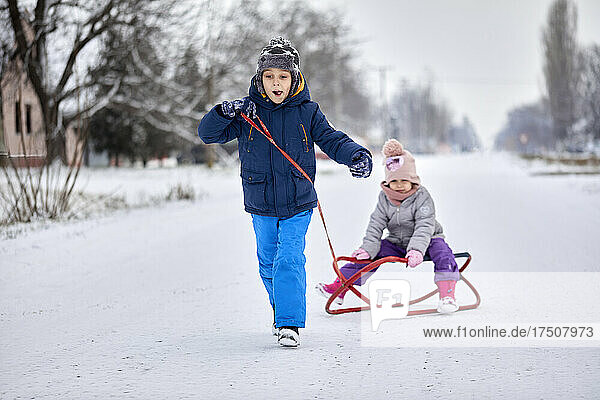 Boy enjoying winter pulling sister on sled