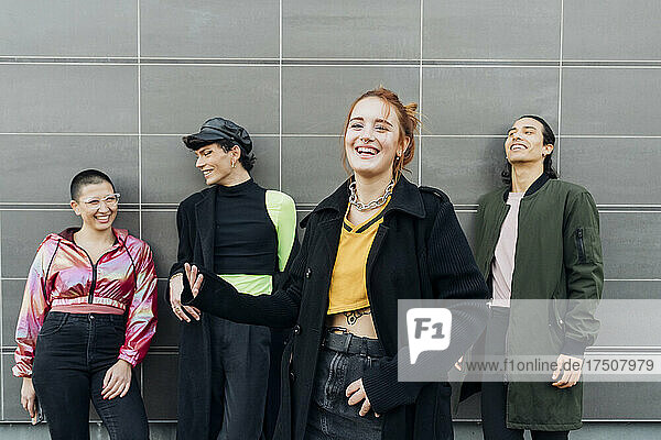 Lächelnde Frau steht mit Freunden vor der Wand