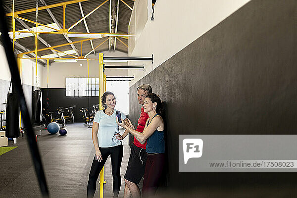 Athlete sharing mobile phone with friends in gym