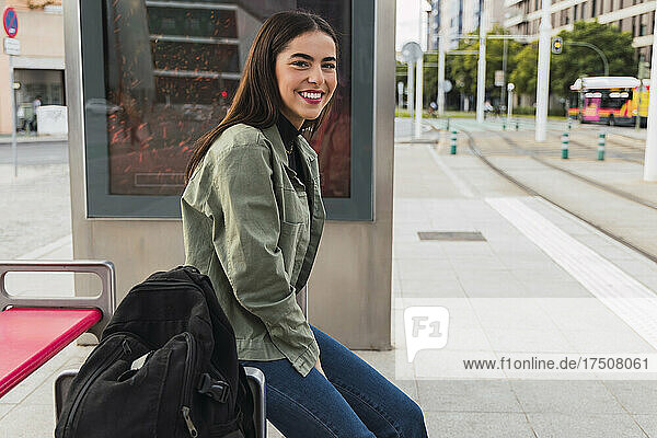 Smiling woman with backpack at tram station platform