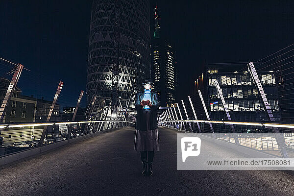 Businesswoman with virtual reality headset standing on bridge in city