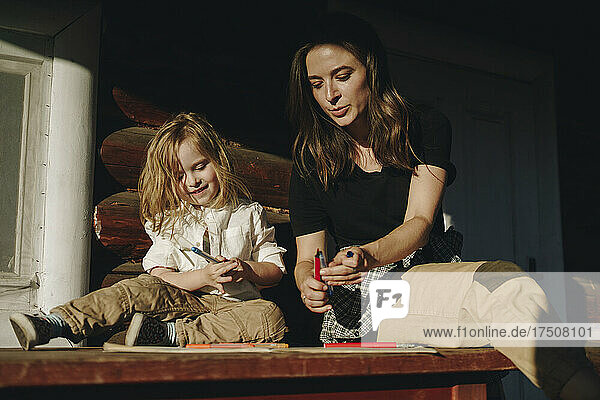 Mother and daughter drawing on book at bench