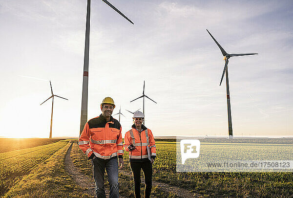 Lächelnde Ingenieure in reflektierender Kleidung im Windpark