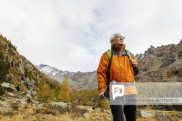 Senior hiker wearing eyeglasses looking away at Rhaetian Alps  Italy