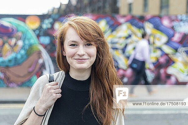 Young redhead woman smiling at street