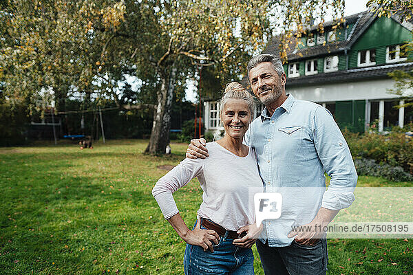 Smiling man standing with arm around woman at backyard