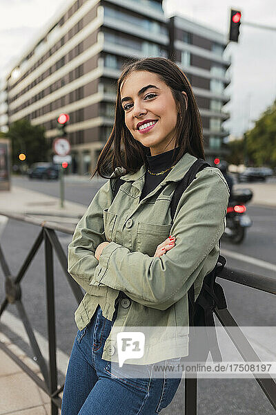 Smiling woman with arms crossed at city street
