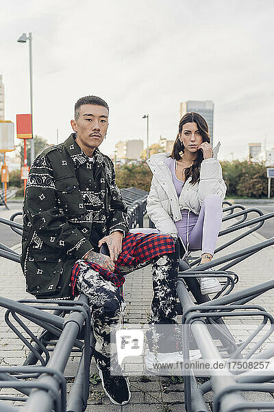 Couple in casual clothing sitting at bicycle parking station