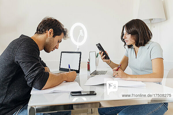 Young male and female freelancer working together on table at home