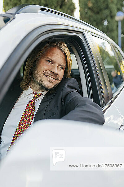 Lächelnder Geschäftsmann  der aus dem Autofenster schaut