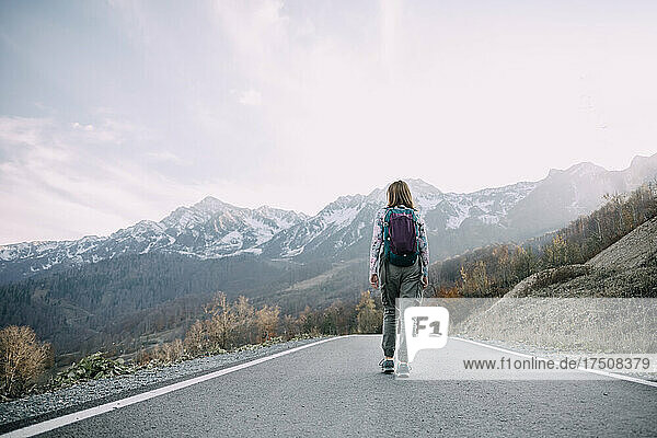 Backpacker hiking on road toward mountains