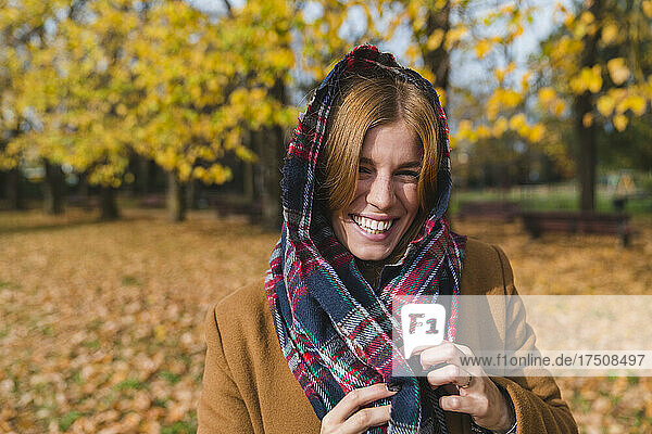 Cheerful woman wearing scarf on head in autumn park