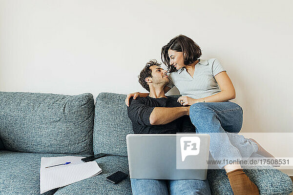 Smiling young couple looking at each other while working at home