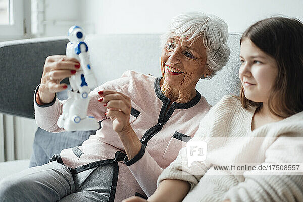 Grandmother showing robot toy to granddaughter at home
