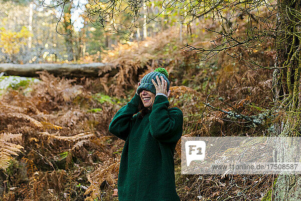 Cheerful woman wearing knit hat in autumn forest