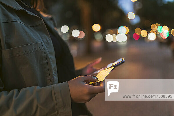 Woman holding credit card and mobile phone on road